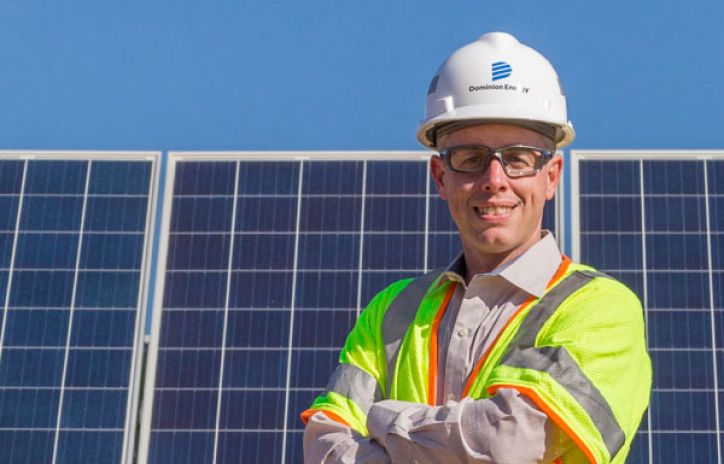 construction worker posing in front of solar panels